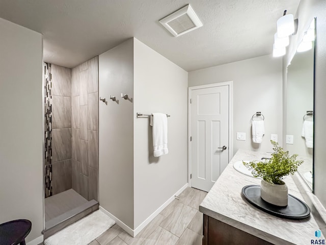 full bathroom with visible vents, baseboards, walk in shower, double vanity, and a textured ceiling