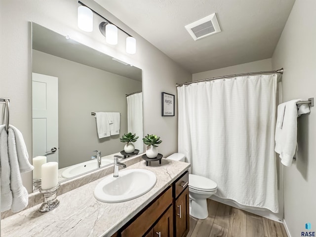 bathroom featuring vanity, a shower with curtain, wood finished floors, visible vents, and toilet