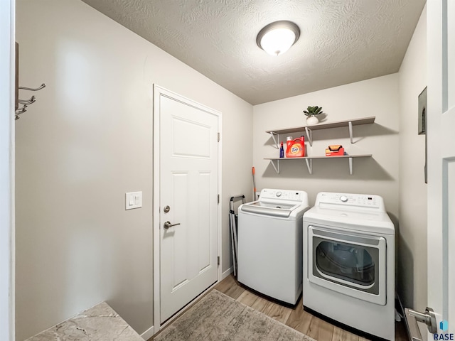 laundry area featuring light wood-style floors, independent washer and dryer, laundry area, and a textured ceiling