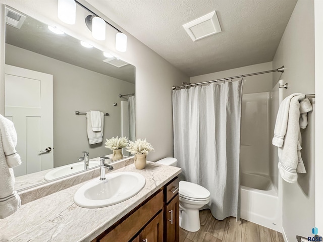 bathroom featuring visible vents, toilet, wood finished floors, and a textured ceiling