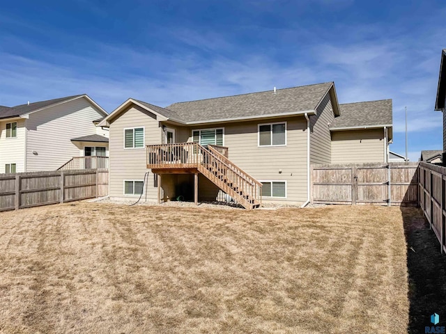 back of property with a shingled roof, stairway, a wooden deck, a lawn, and a fenced backyard