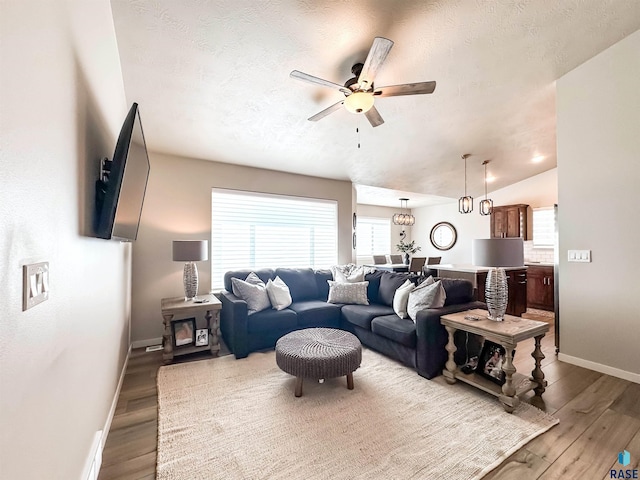 living area featuring a textured ceiling, lofted ceiling, ceiling fan, and wood finished floors