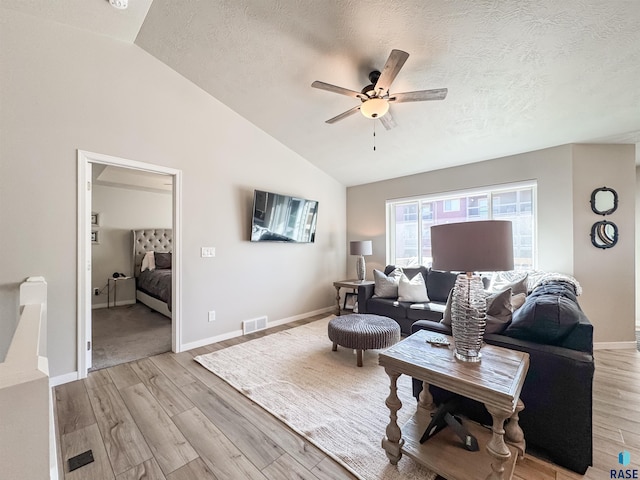 living area with lofted ceiling, light wood-style floors, visible vents, and a textured ceiling