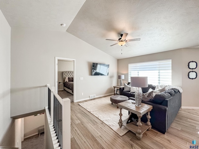 living room featuring visible vents, ceiling fan, light wood-type flooring, lofted ceiling, and a textured ceiling