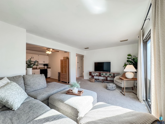 living area with visible vents, light colored carpet, and ceiling fan