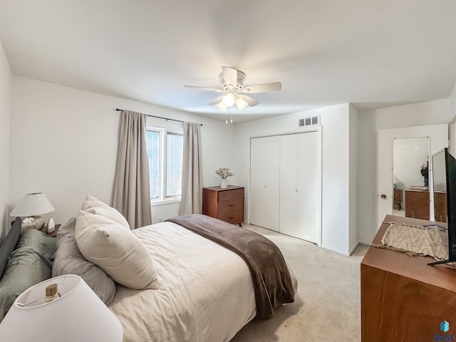 bedroom with visible vents, light colored carpet, a closet, and ceiling fan