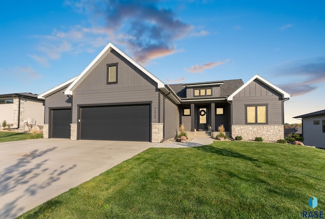 view of front of house featuring board and batten siding, a front yard, driveway, stone siding, and an attached garage