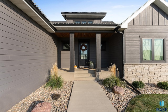 entrance to property featuring stone siding, board and batten siding, and covered porch