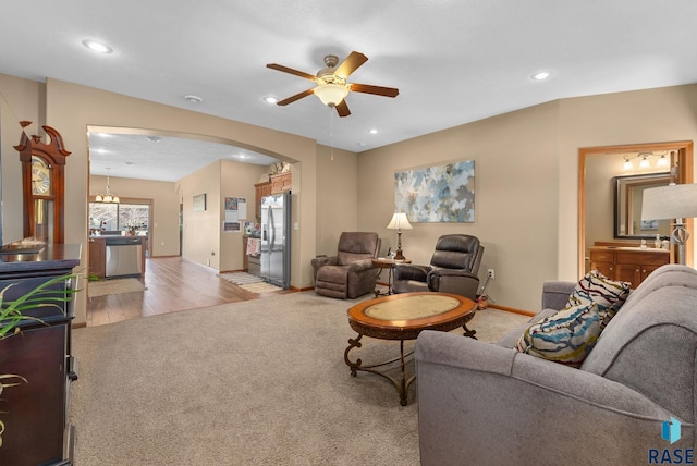 carpeted living room featuring recessed lighting, a ceiling fan, arched walkways, and baseboards