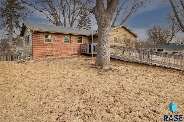 rear view of house with crawl space, brick siding, and a wooden deck