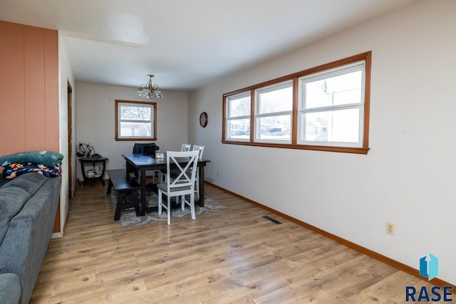 dining area with visible vents, baseboards, light wood-style floors, and a chandelier