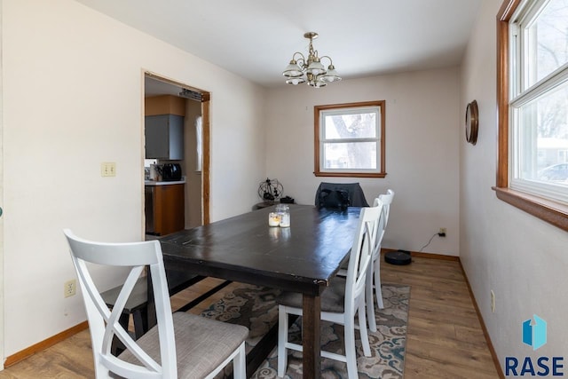 dining room with light wood-type flooring, baseboards, and a chandelier