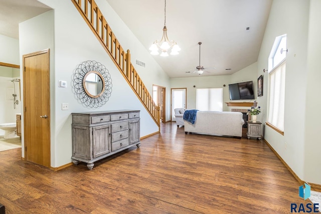 living area with stairway, dark wood-style floors, visible vents, and high vaulted ceiling