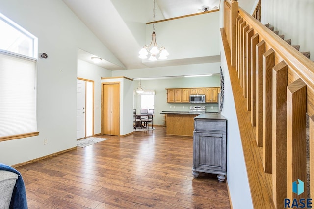 kitchen featuring dark countertops, stainless steel appliances, baseboards, a chandelier, and dark wood-style flooring