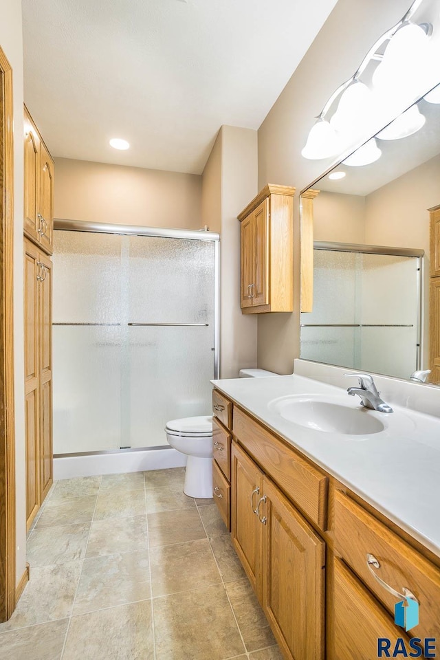 full bathroom with toilet, a stall shower, and vanity