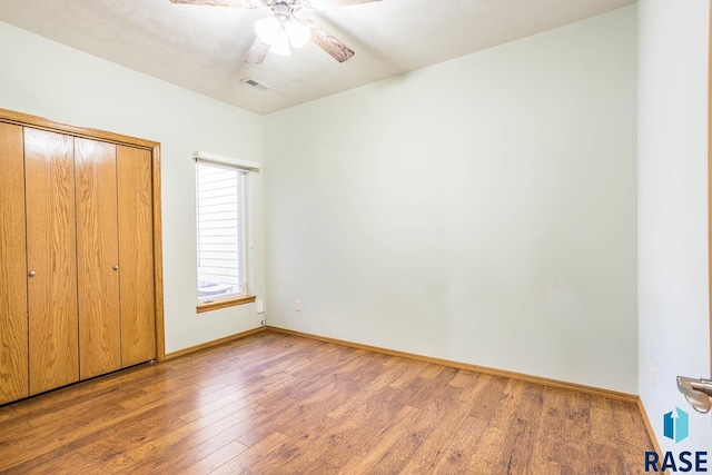 unfurnished bedroom featuring visible vents, a ceiling fan, a closet, wood-type flooring, and baseboards