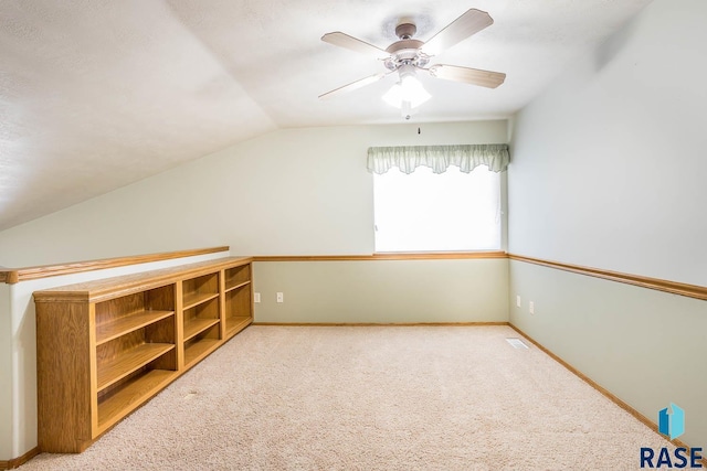 additional living space with visible vents, baseboards, lofted ceiling, carpet flooring, and a ceiling fan