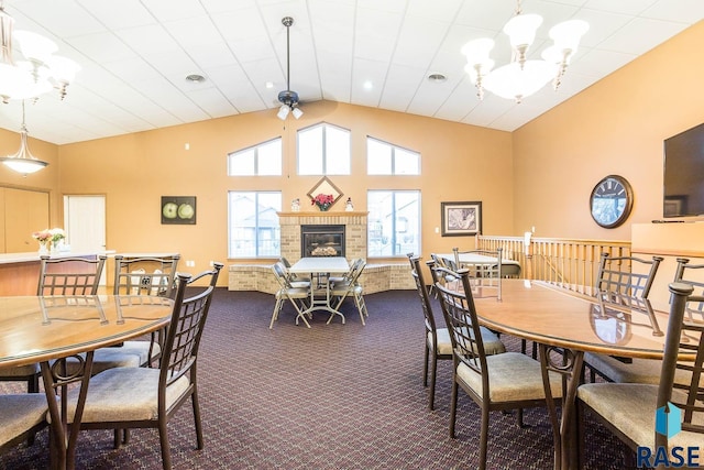 carpeted dining space featuring visible vents, a fireplace, high vaulted ceiling, and an inviting chandelier