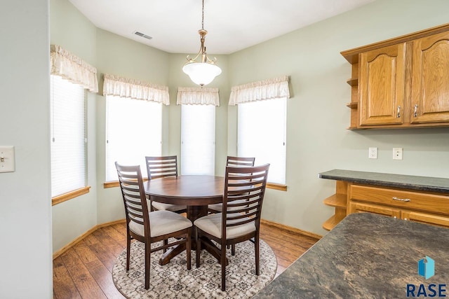 dining area featuring a healthy amount of sunlight, visible vents, wood-type flooring, and baseboards