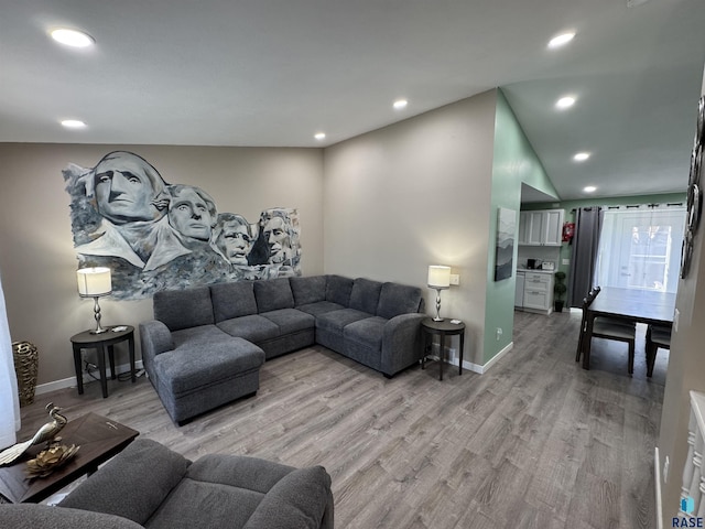 living room with recessed lighting, light wood-style flooring, lofted ceiling, and baseboards