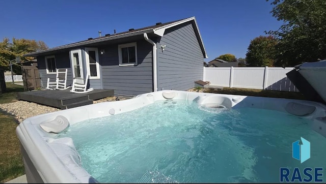 rear view of house featuring fence and a hot tub