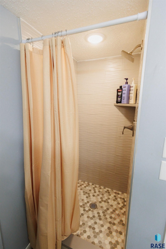 bathroom with a shower stall and a textured ceiling