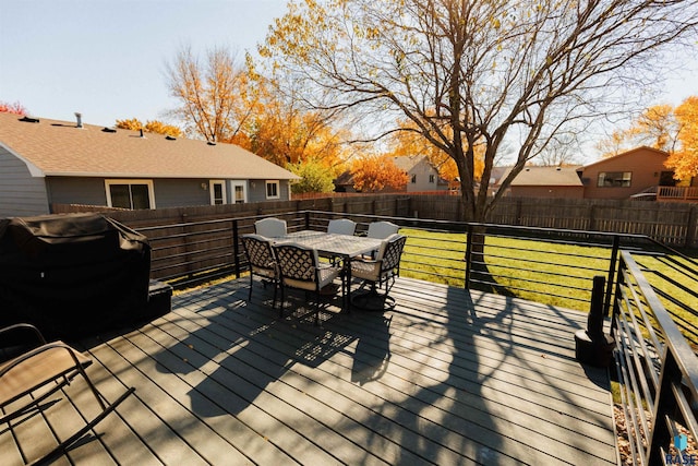 wooden deck featuring outdoor dining area, a lawn, area for grilling, and a fenced backyard