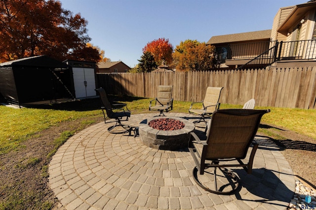 view of patio featuring a storage shed, fence, an outdoor structure, and a fire pit