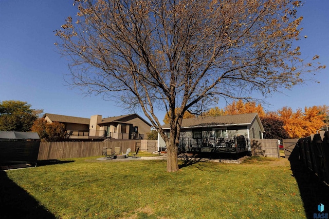 view of yard featuring a wooden deck, a fenced backyard, and an outdoor fire pit