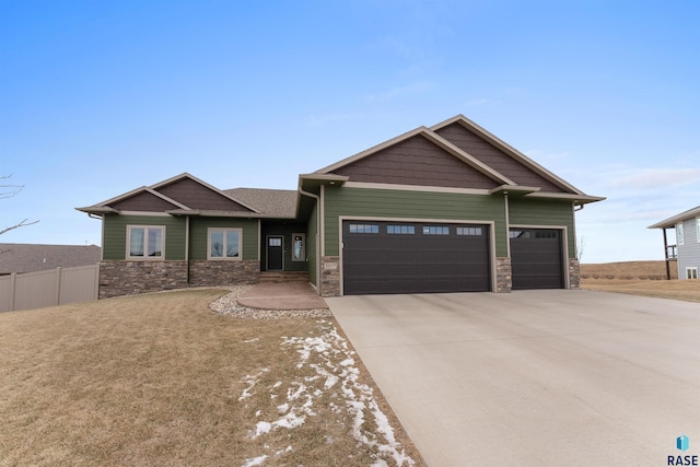 craftsman house featuring stone siding, an attached garage, concrete driveway, and fence