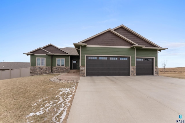 craftsman-style house featuring concrete driveway, fence, a garage, and stone siding