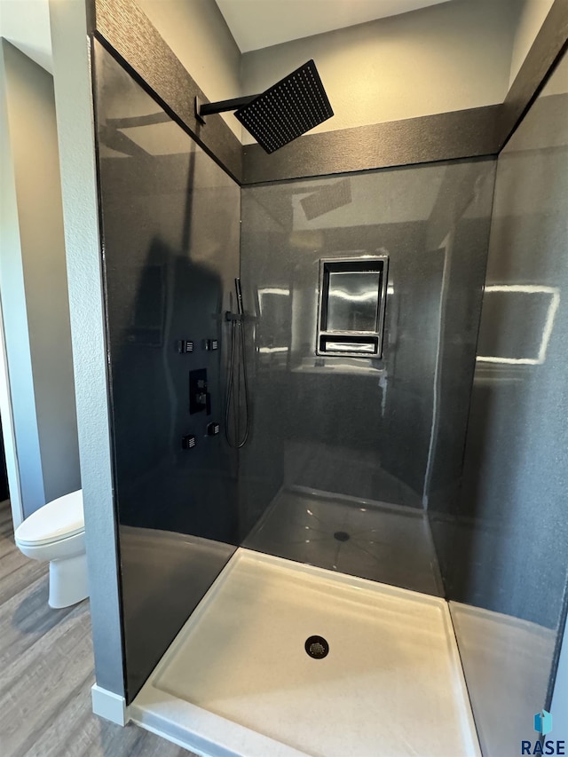 full bath featuring elevator, wood finished floors, toilet, and a walk in shower