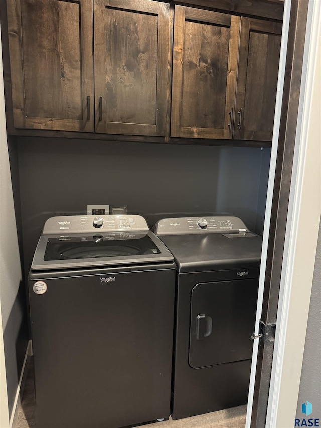 clothes washing area featuring washer and dryer and cabinet space