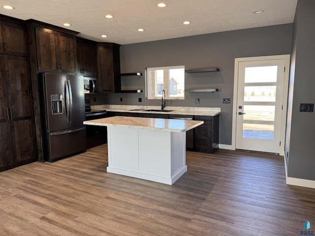 kitchen with black fridge, open shelves, a sink, a kitchen island, and dark brown cabinetry