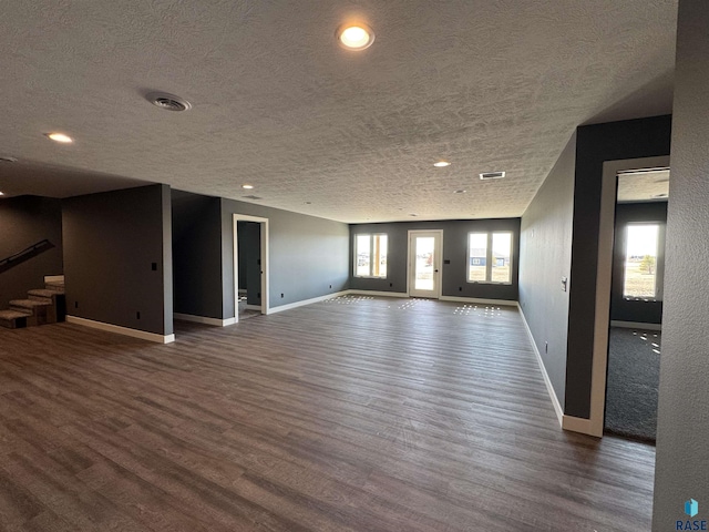 unfurnished living room featuring visible vents, stairs, baseboards, and wood finished floors