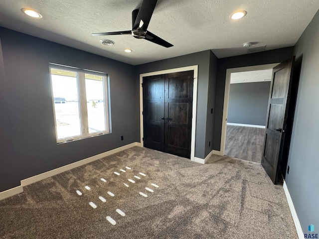 unfurnished bedroom with carpet, visible vents, baseboards, a closet, and a textured ceiling