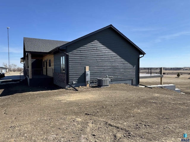 view of property exterior featuring cooling unit and roof with shingles