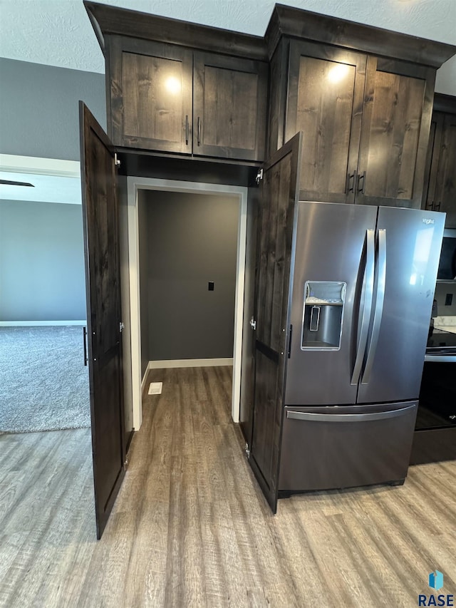 kitchen with baseboards, dark brown cabinetry, light wood-style flooring, and stainless steel fridge with ice dispenser