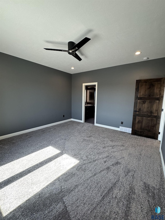 carpeted spare room with a textured ceiling, a ceiling fan, visible vents, and baseboards