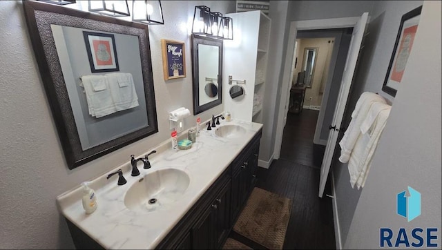 bathroom with double vanity, wood finished floors, and a sink