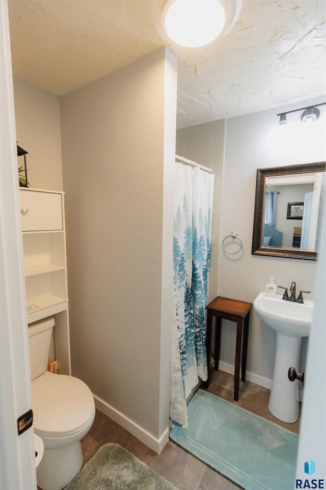 full bath featuring curtained shower, toilet, baseboards, and a sink