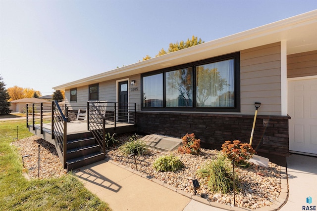 view of front of property featuring stone siding and a deck