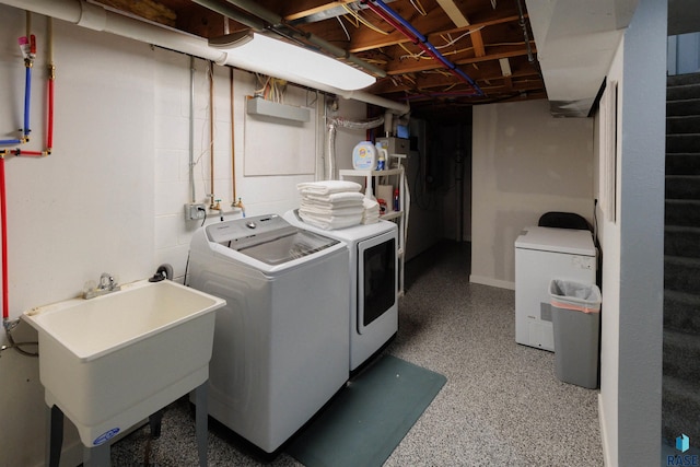 laundry room with laundry area, separate washer and dryer, and a sink