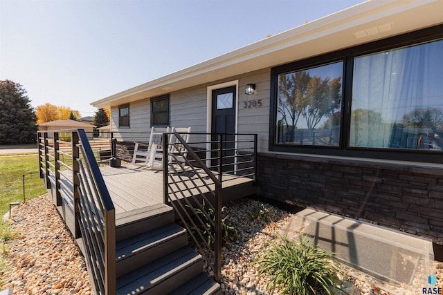 view of exterior entry featuring a deck and stone siding