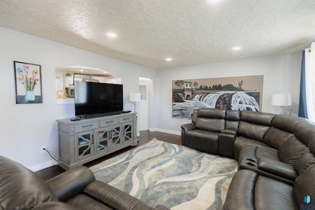 living room with dark wood finished floors, recessed lighting, a textured ceiling, and baseboards