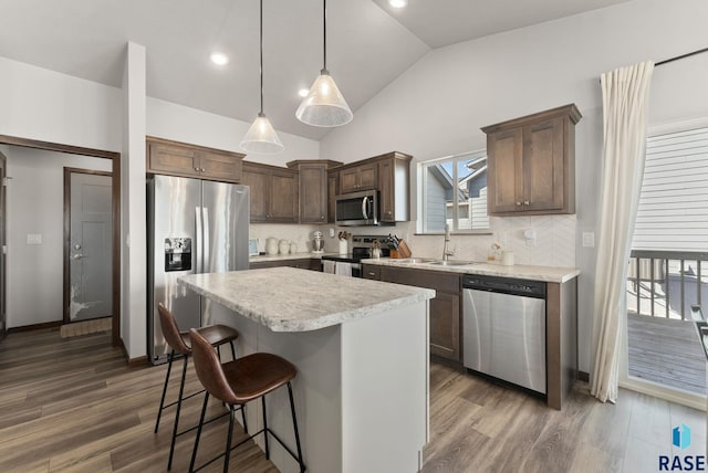 kitchen with a sink, appliances with stainless steel finishes, a kitchen breakfast bar, and dark wood-style flooring