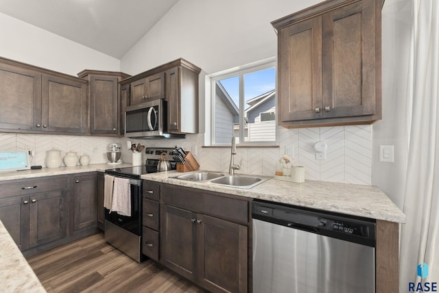 kitchen featuring dark wood-style floors, lofted ceiling, a sink, dark brown cabinets, and appliances with stainless steel finishes