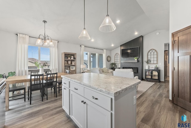 kitchen with light wood-type flooring, lofted ceiling, a center island, and light countertops