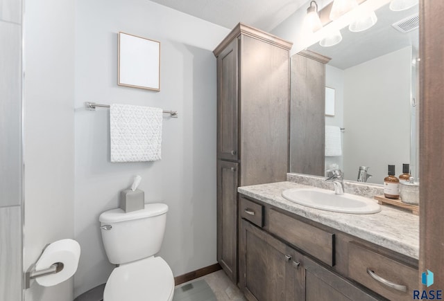 bathroom with vanity, toilet, baseboards, and visible vents