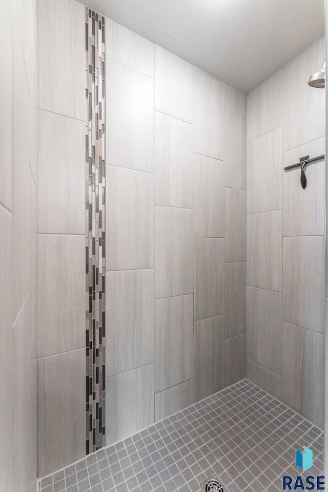 bathroom with a tile shower and a textured ceiling